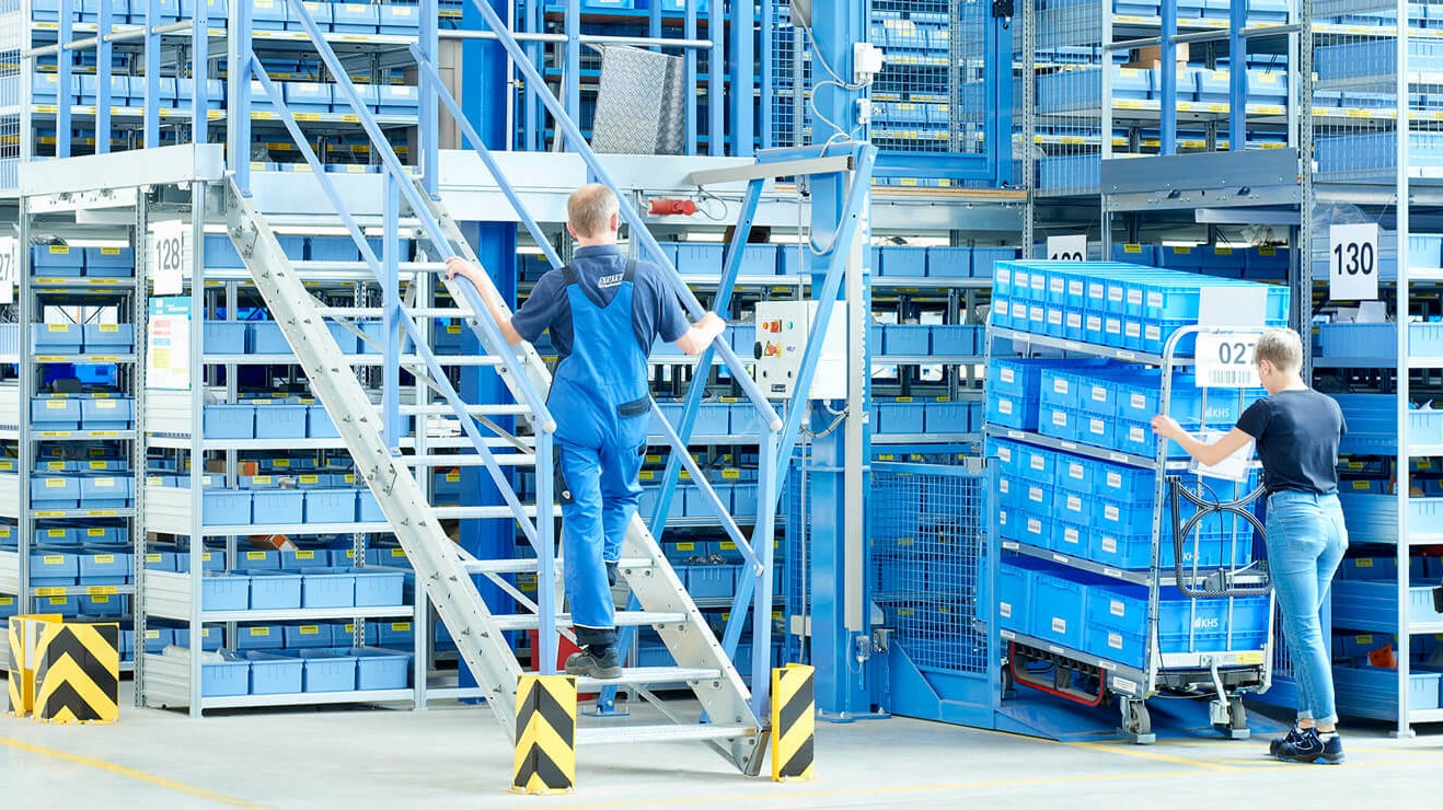 Mitarbeiter an einer Mehrgeschossanlage mit Fachbodenregalen