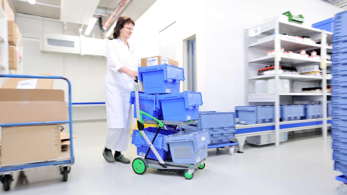 Eine Mitarbeiterin bewegt mehrere BITO Mehrwegbehälter durch ein Lager