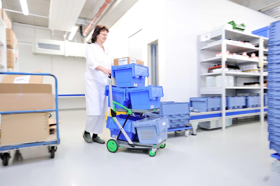 Eine Mitarbeiterin bewegt mehrere BITO Mehrwegbehälter durch ein Lager