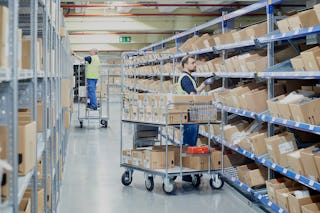 Zwei Mitarbeiter an BITO Durchlaufregalen mit Schrägböden und an einem Fachbodenregal