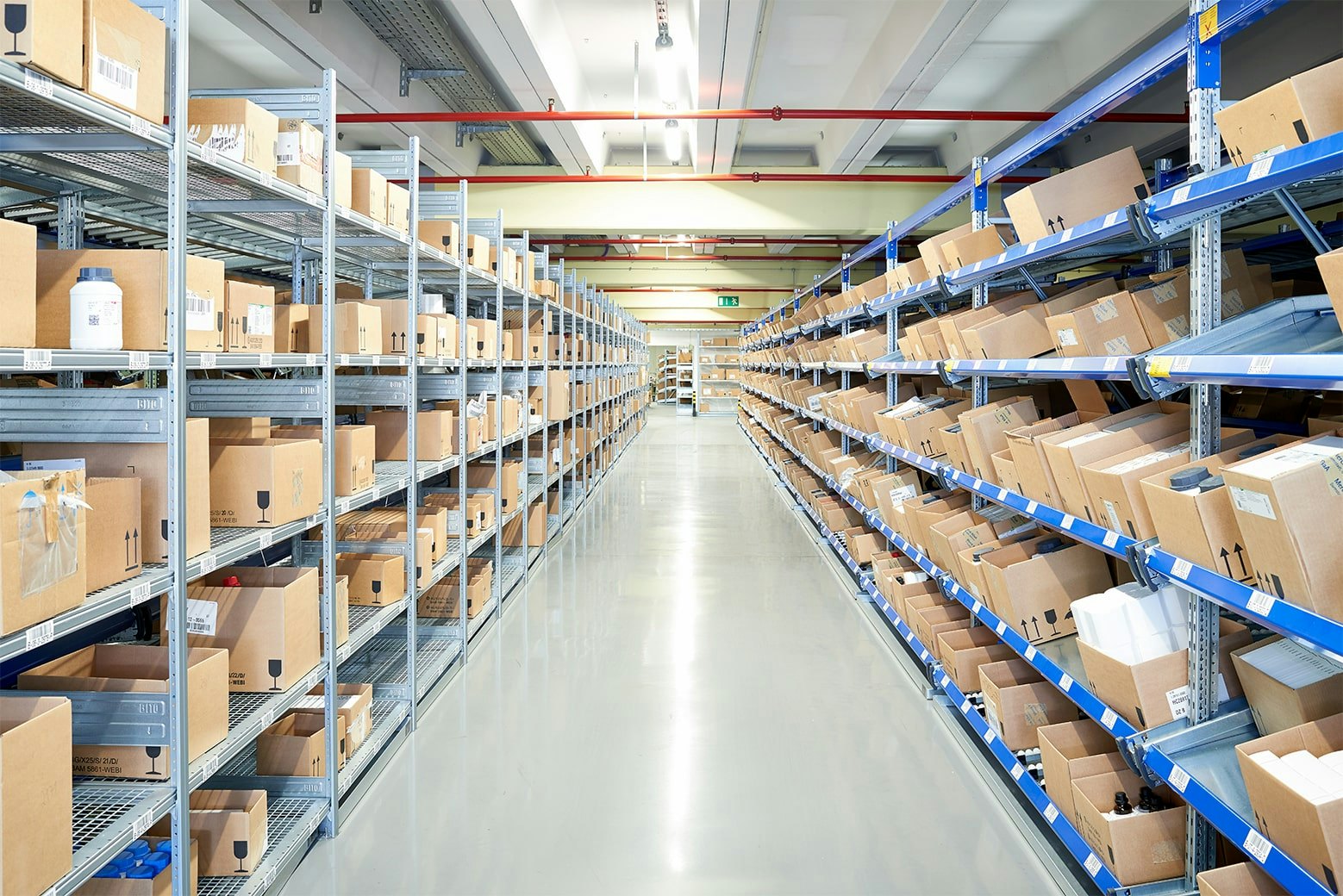 Ein Gang zwischen einem Fachbodenregal und einem Durchlaufregal mit Schrägböden von BITO