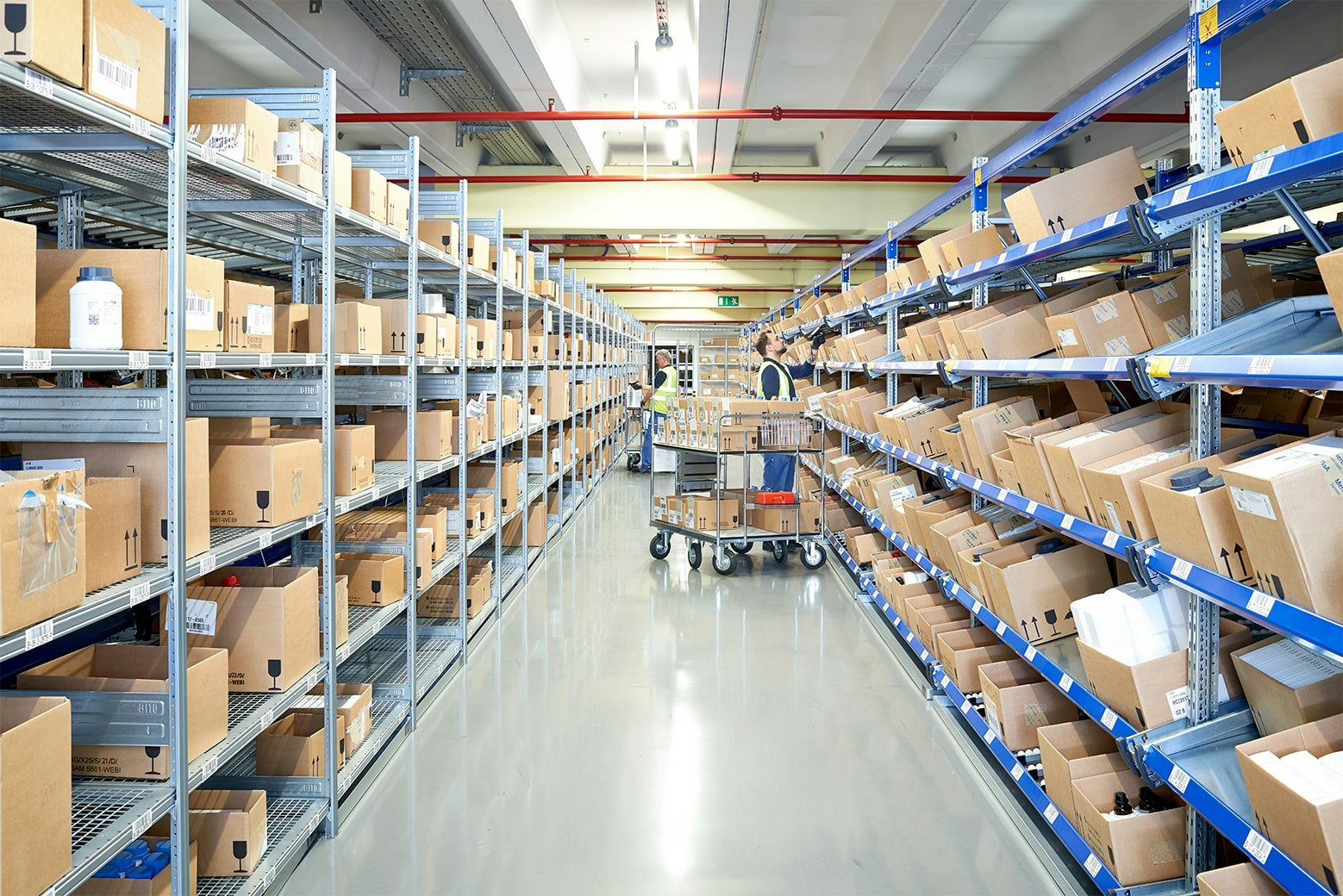 Zwei Mitarbeiter an BITO Durchlaufregalen mit Schrägböden und an einem Fachbodenregal