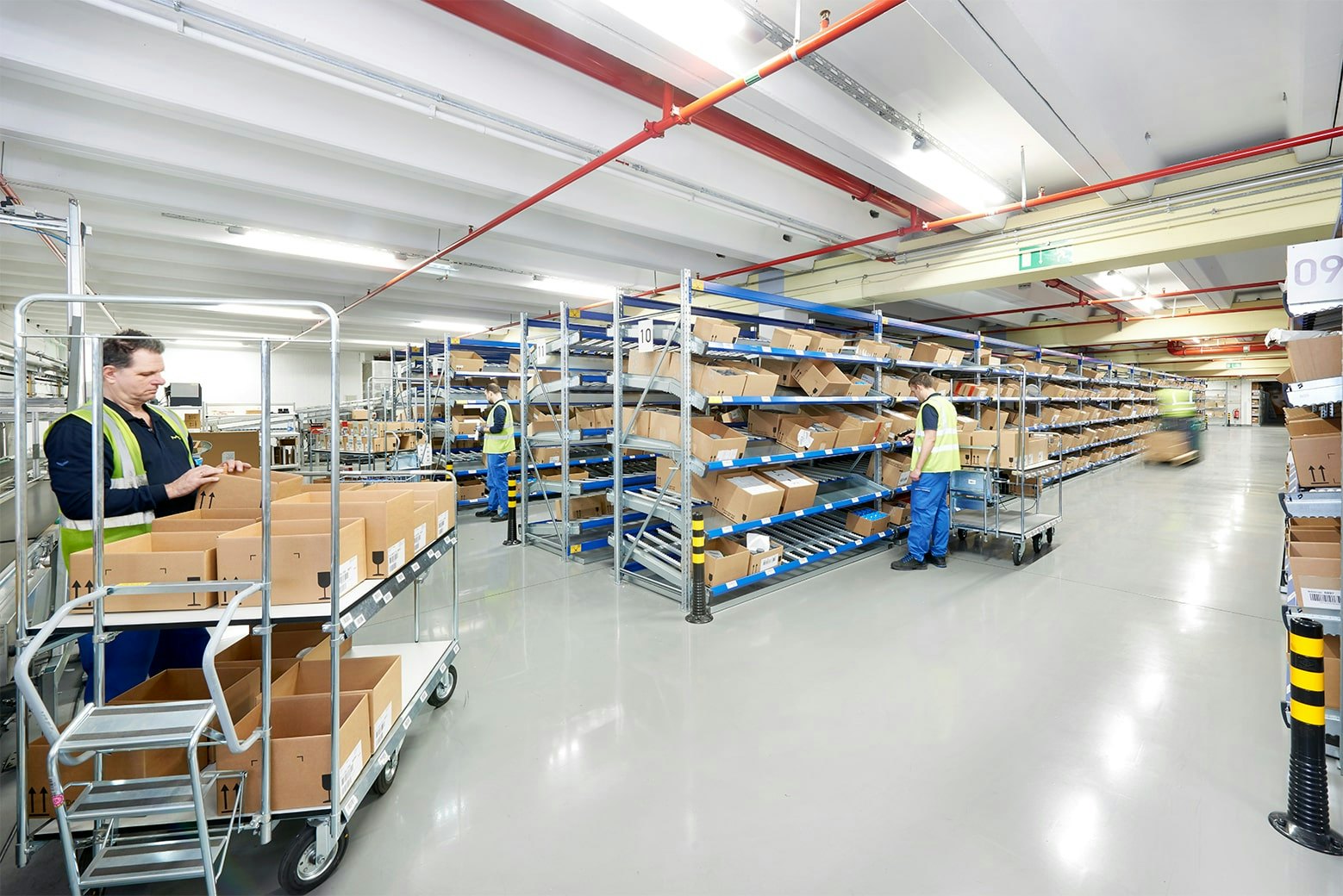 Mehrere Arbeiter an BITO Durchlaufregale mit Schrägböden