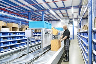 Ein Lagerarbeiter an einer Fördertechnik zwischen BITO Durchlaufregalen