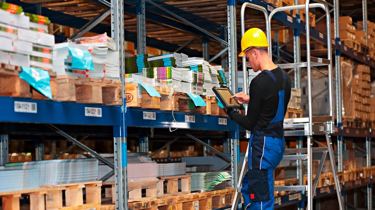 Ein Mann in Arbeitskleidung vor einem Palettenregal