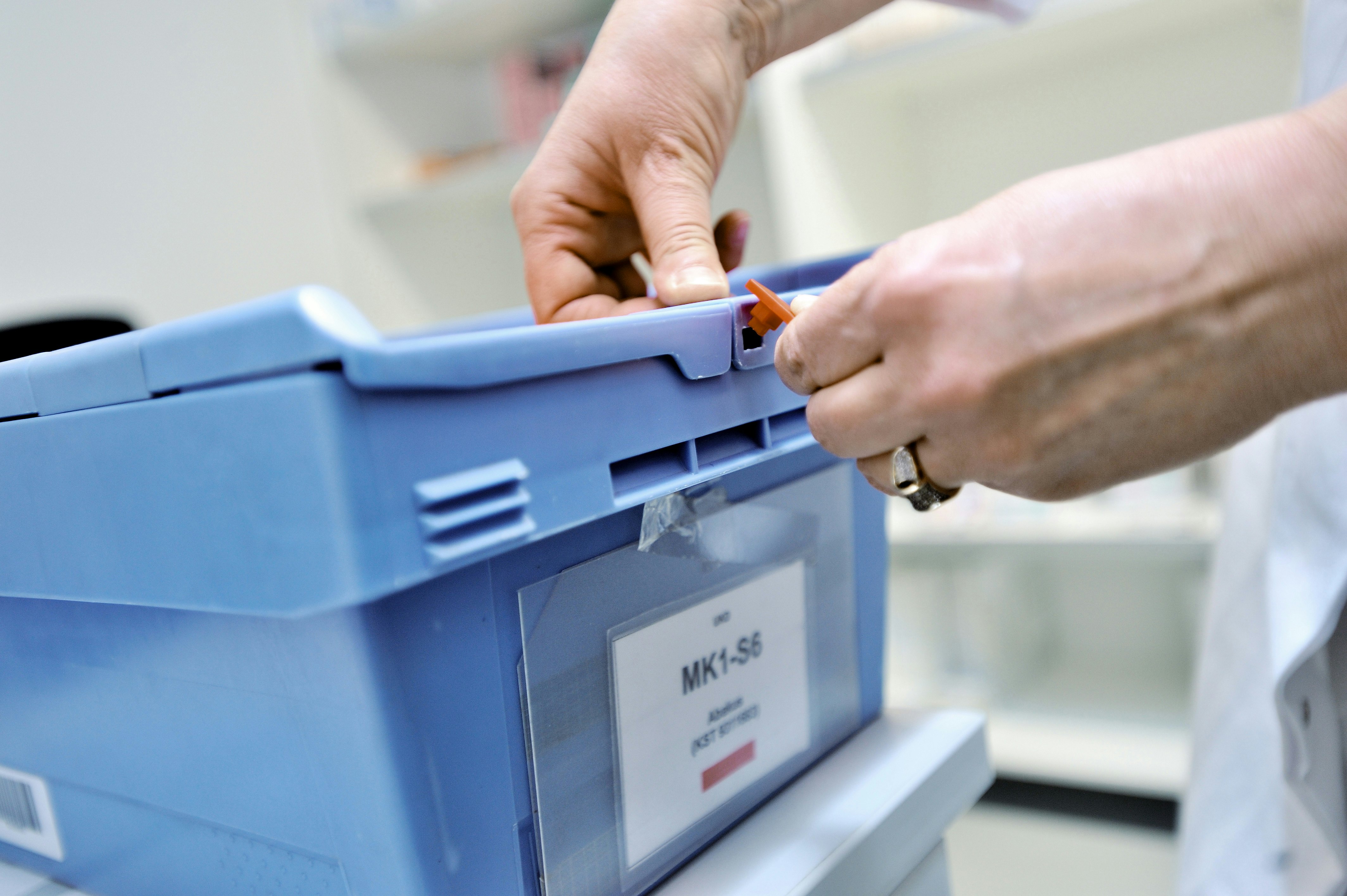 Ein Mitarbeiter verschließt einen Behälter mit einer Plombe