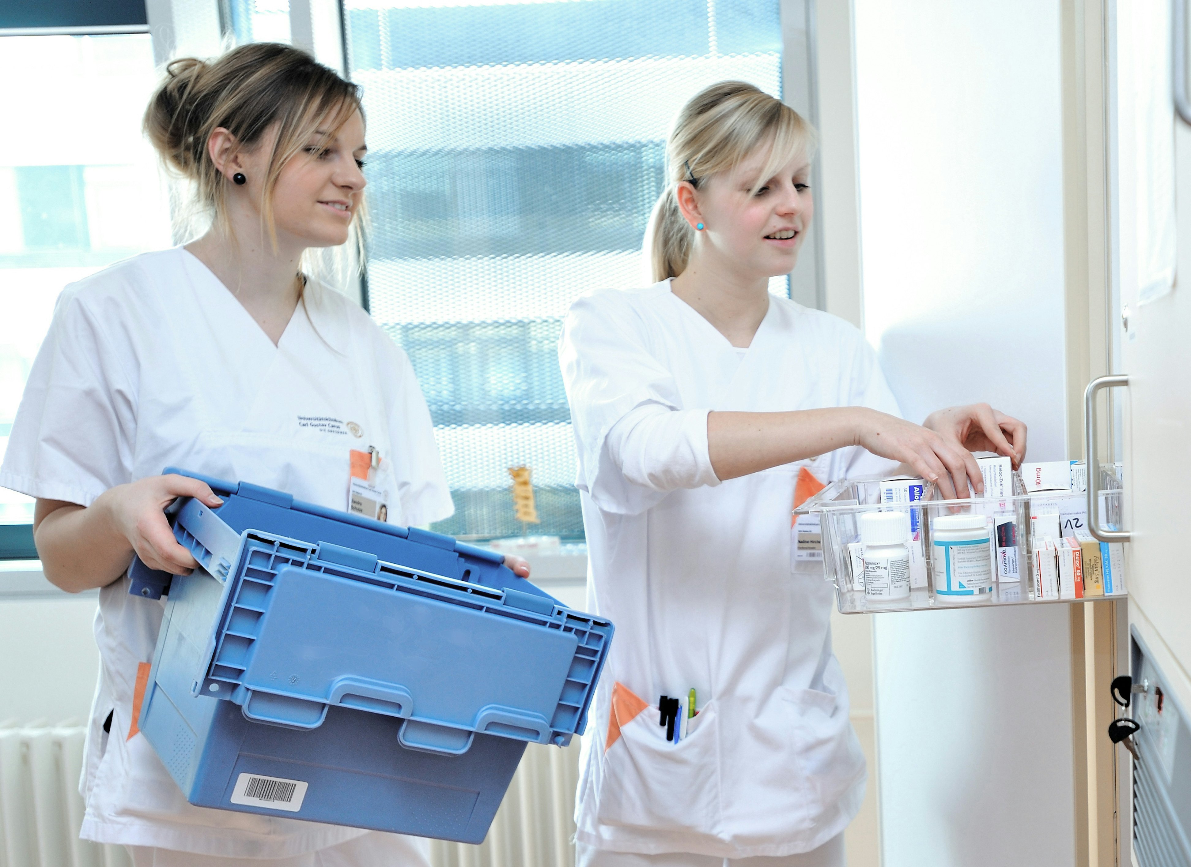 Zwei Ärztinnen räumen Medikamente aus einem BITO Behälter in einen Schrank.