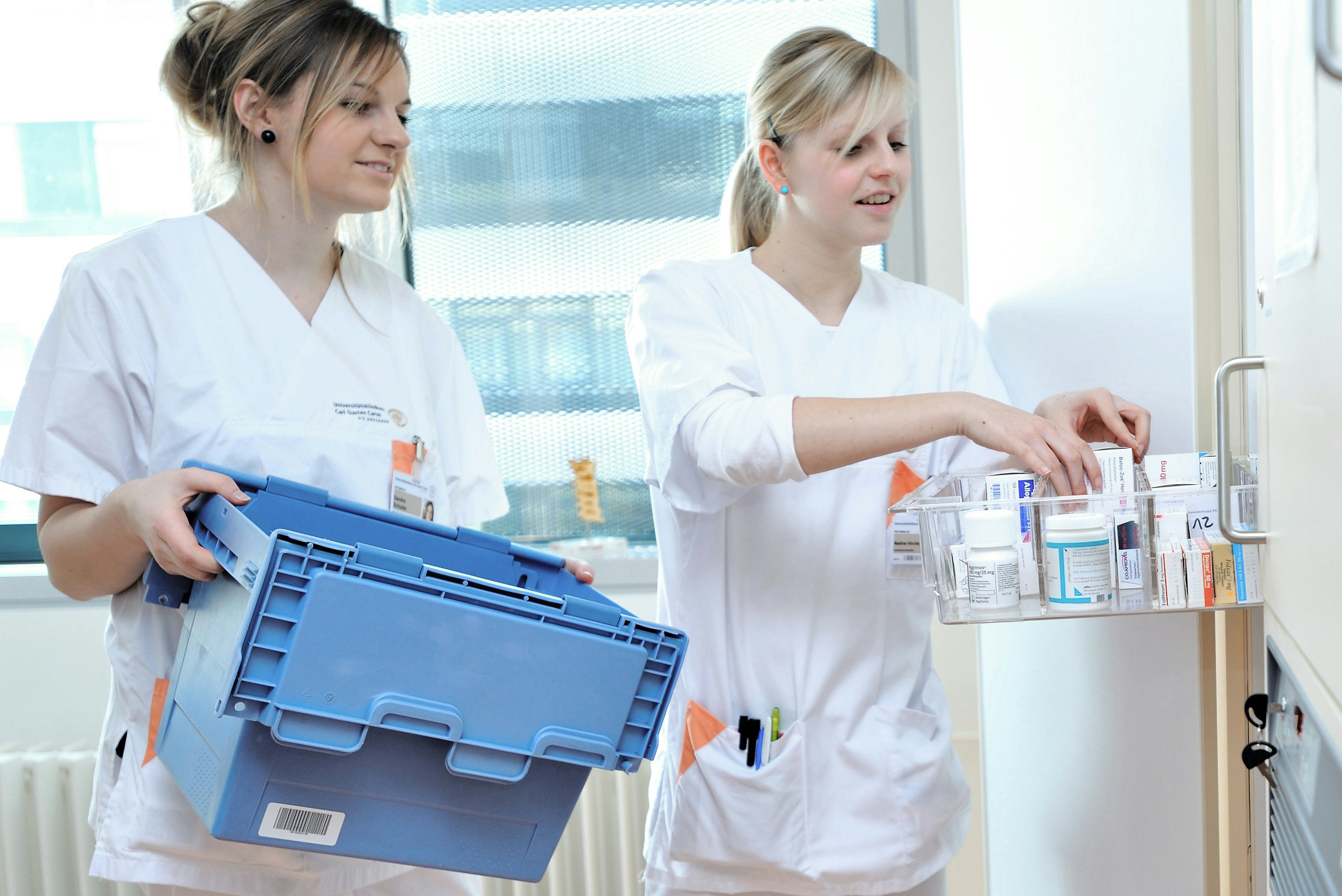 Zwei Ärztinnen räumen Medikamente aus einem BITO Behälter in einen Schrank.