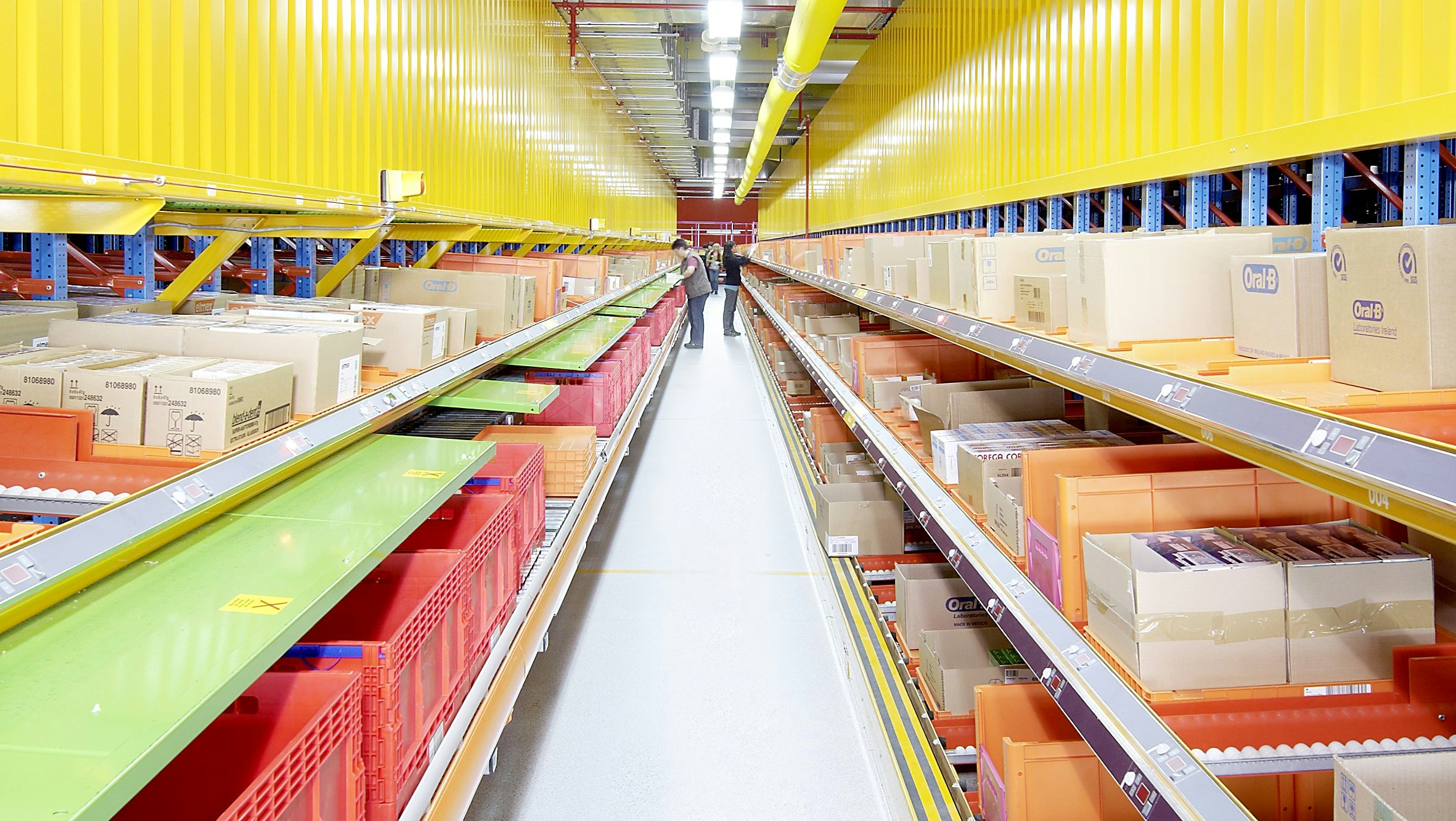 BITO Stückgutdurchlaufregal Zwei Stückgutdurchlaufregale rechts und links sind in der Mitte durch eine langen Gang voneinander getrennt.