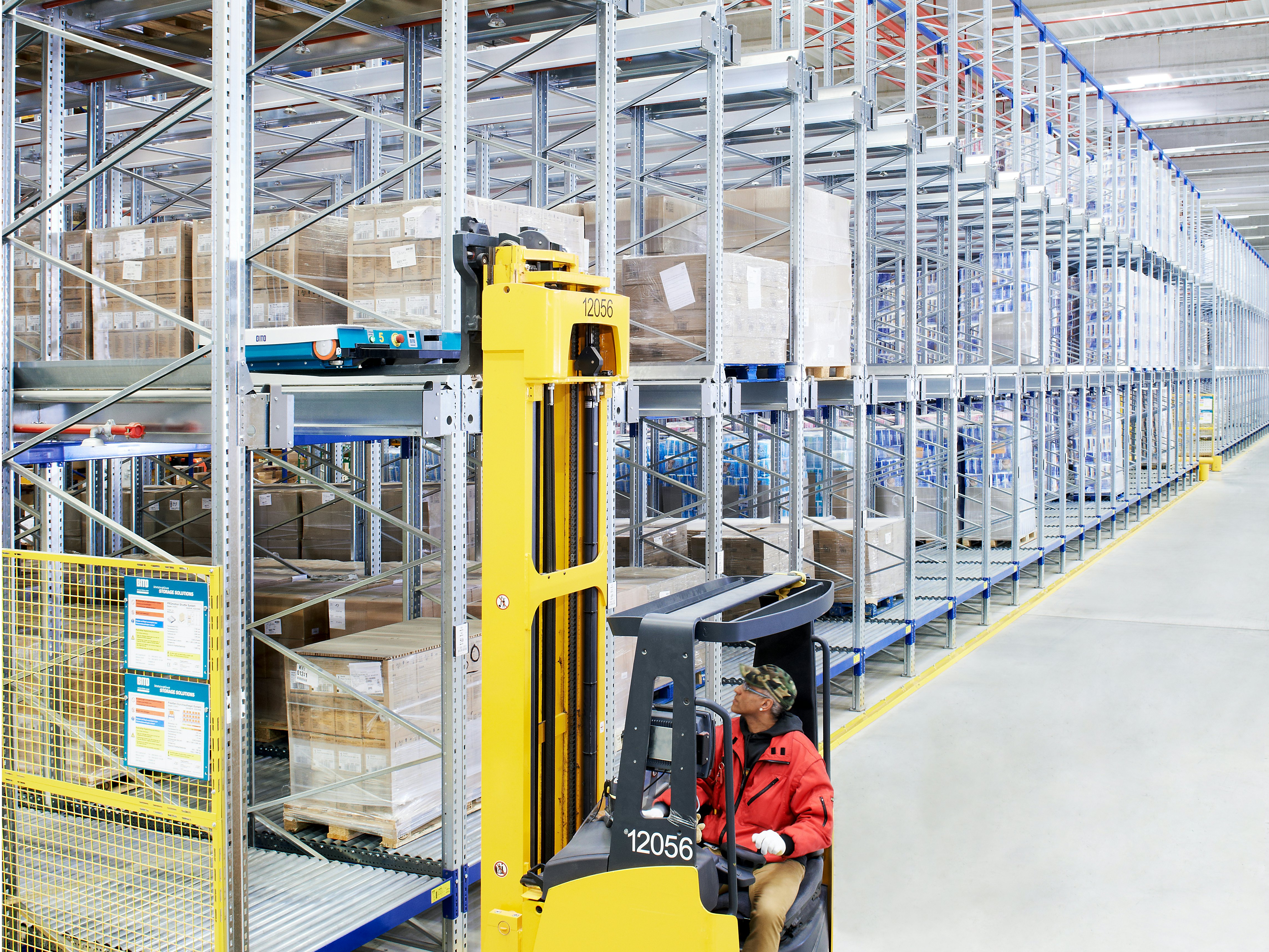 Regały przepływowe paletowe BITO PROflow w połączeniu z kompaktowym systemem magazynowania obsługiwanym wahadłowo Ein Mann holt mit dem Stapler eine Palette aus einem BITO Lagerregal.