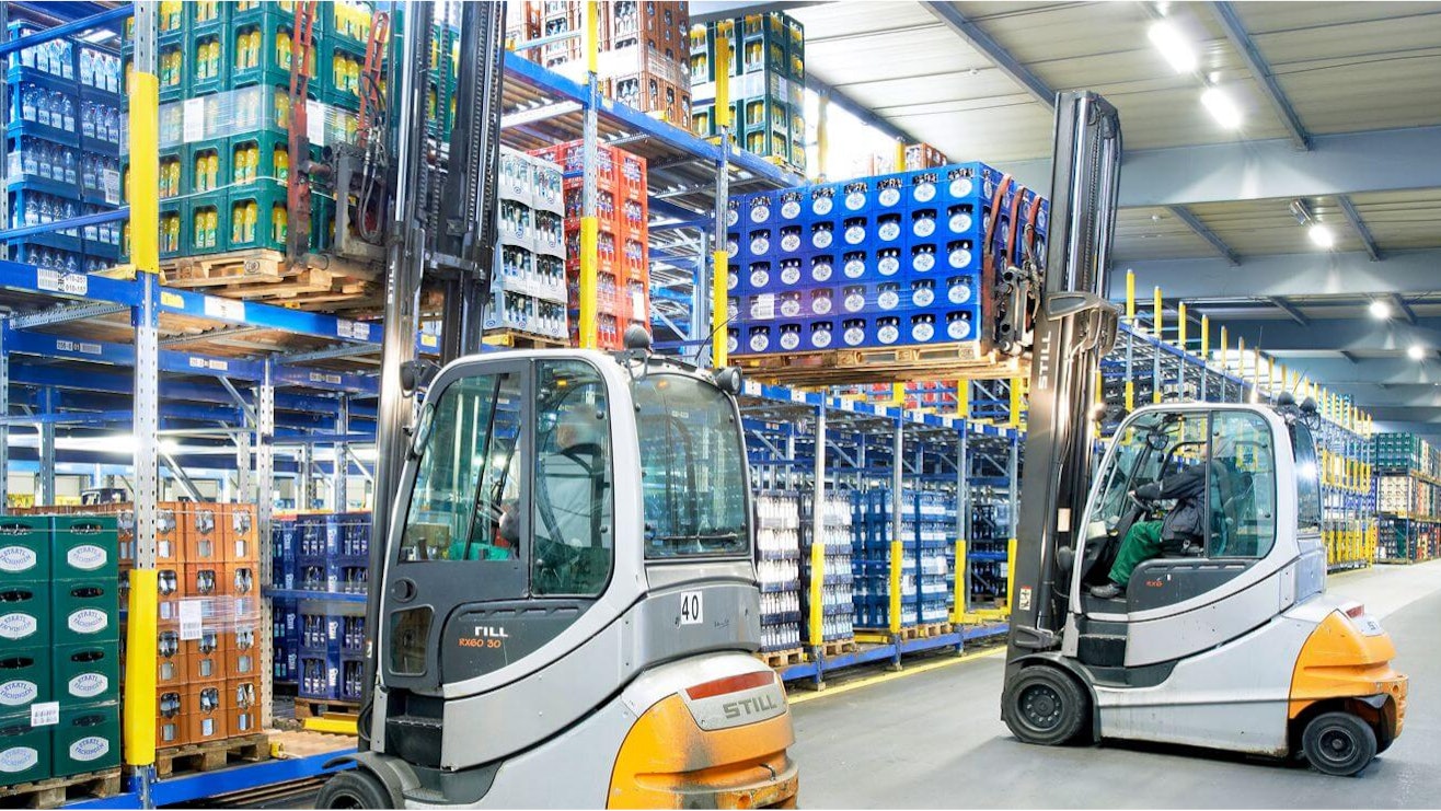 Pallegennemløbsreoler Zwei Stapler verladen Getränkekisten in ein Palettenregal von BITO.