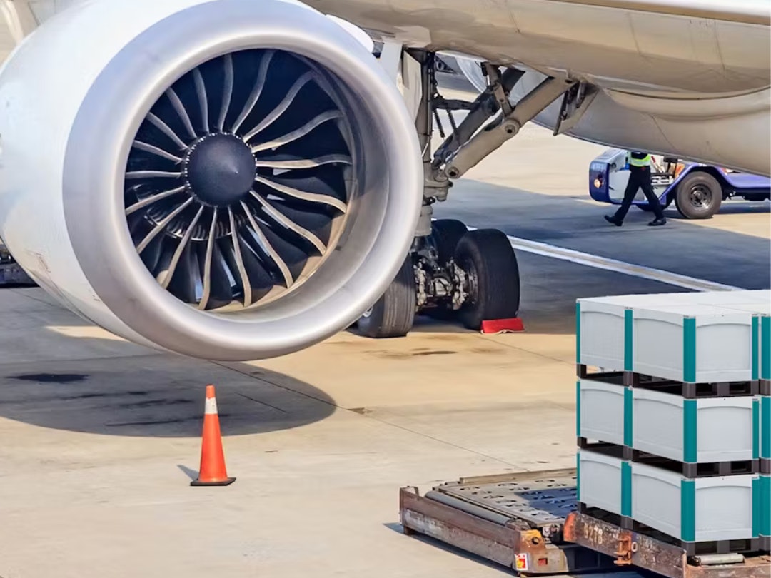 BITO Behälter stehen gestapelt vor dem Triebwerk eines Flugzeugs.