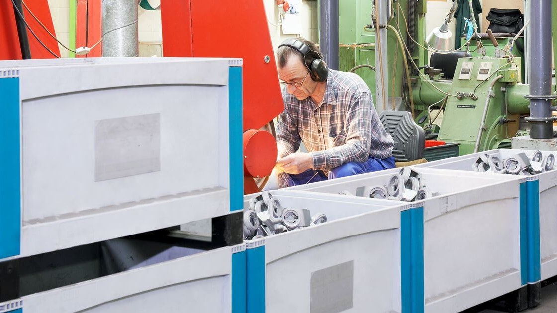 Bacs pour charges lourdes BITO SL Arbeiter von Schubert und Salzer Maschinenbau arbeiten an Maschinen. Die bereits fertigen Produkte werden in BITO Behältern gelagert.