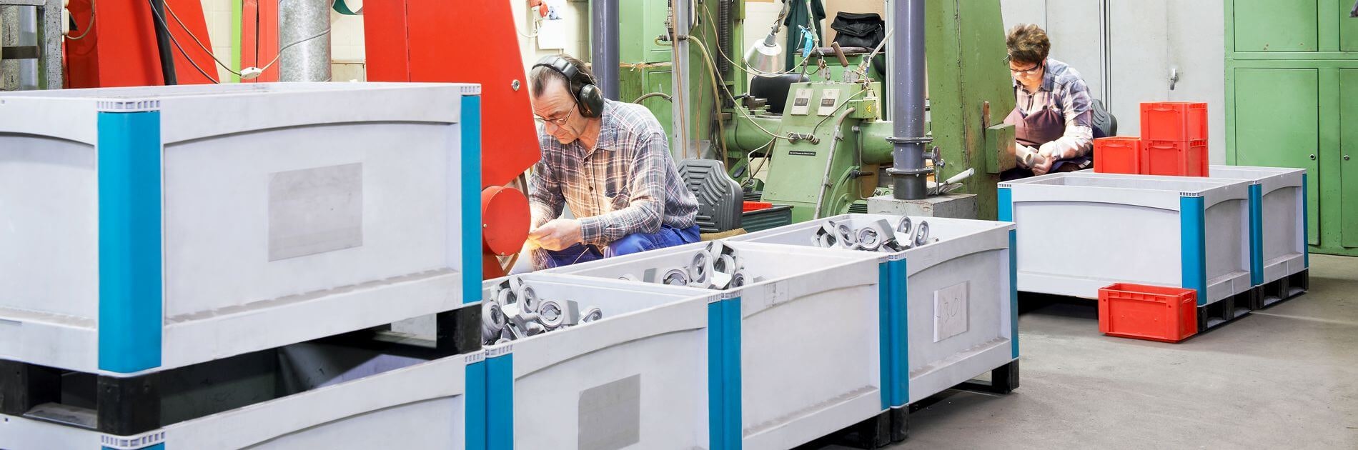 BITO Schwerlastbehälter SL Arbeiter von Schubert und Salzer Maschinenbau arbeiten an Maschinen. Die bereits fertigen Produkte werden in BITO Behältern gelagert.