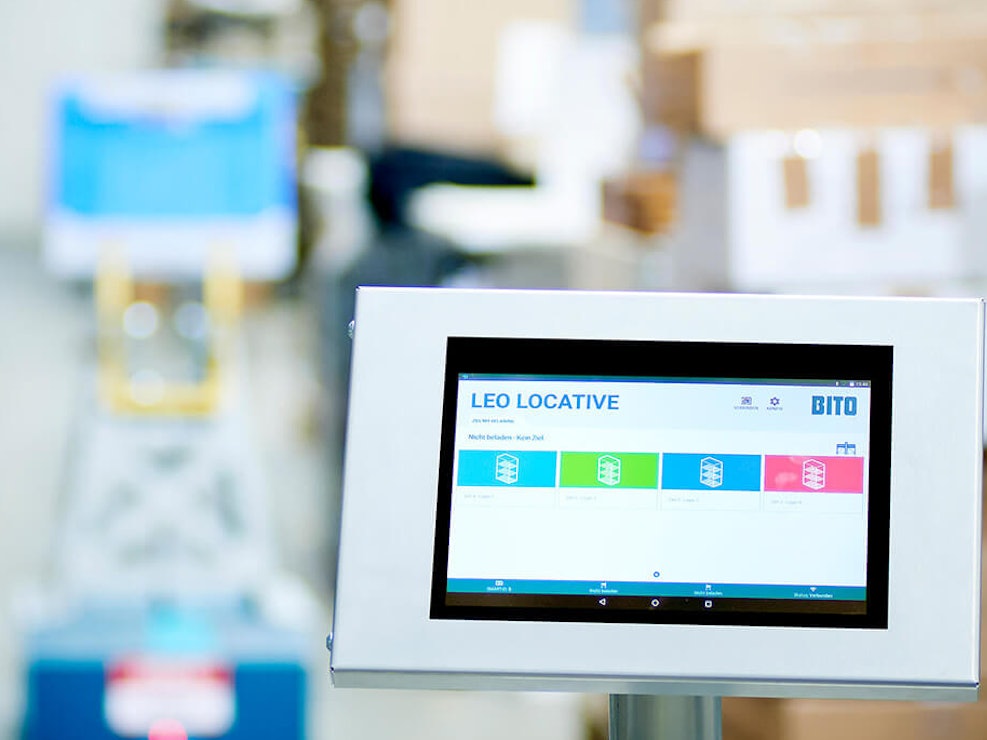 BITO LEO App Das Tablet zum Steuern vom LEO Locative steht im Vordergrund. Dahinter sieht man einen LEO fahren.