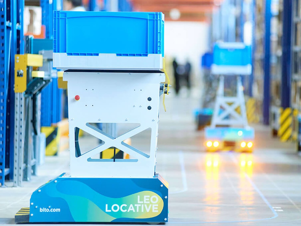 BITO LEO Der LEO Locative fährt auf seiner geklebten Spur zwischen BITO Regalen entlang. Er transportiert einen BITO Behälter.
