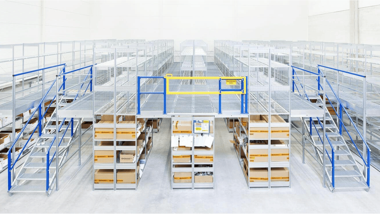 BITOn monitasoiset asennukset Ein BITO Regal, das in der ersten Etage mit Paketen gefüllt ist. Eine Treppe führt zur zweiten Etage, die allerdings noch leer ist.