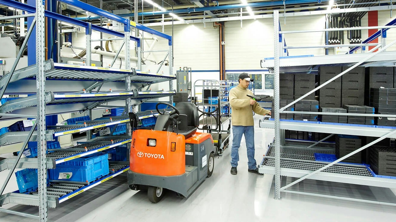 BITO Carton live storage racking Ein Mann steht in der Mitte zwischen zwei BITO Regalen und scannt eine Kiste aus einem BITO Regal.