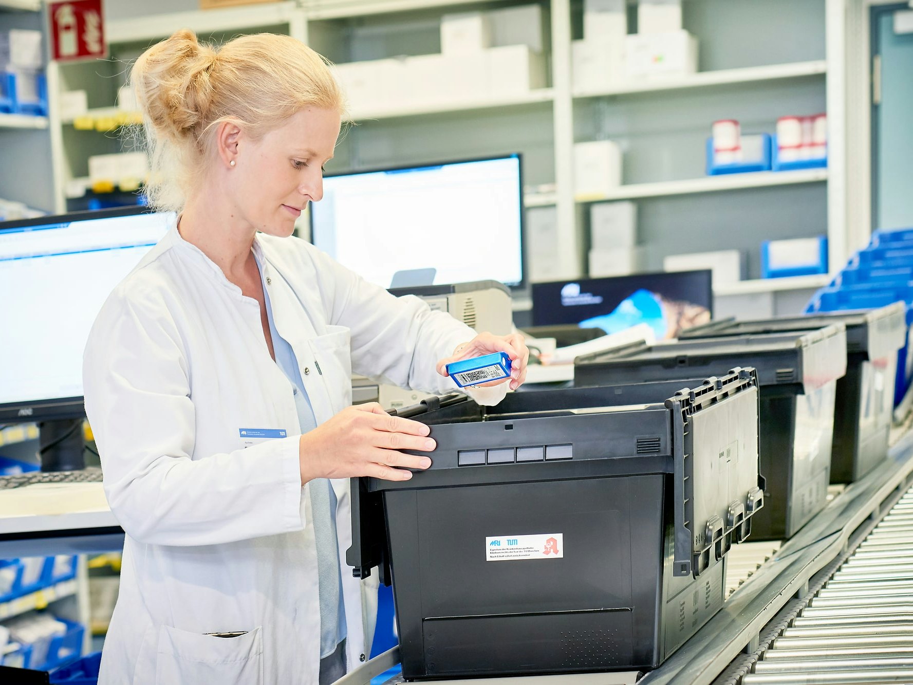 Mitarbeiterin des Uniklinikum München packt einen Mehrwegbehälter