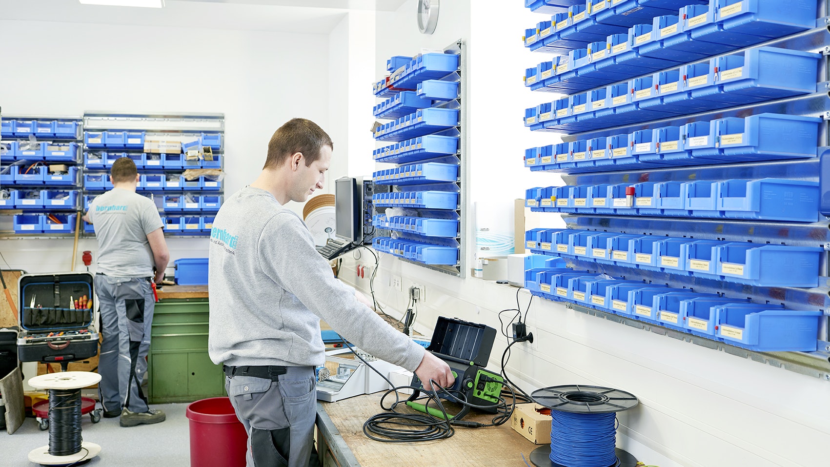 BITO Kommissionierwand In der Werkstatt von Elektro Bernhard GmbH hängen BITO Regale mit kleinen BITO Behältern als Kleinteilelager an der Wand.