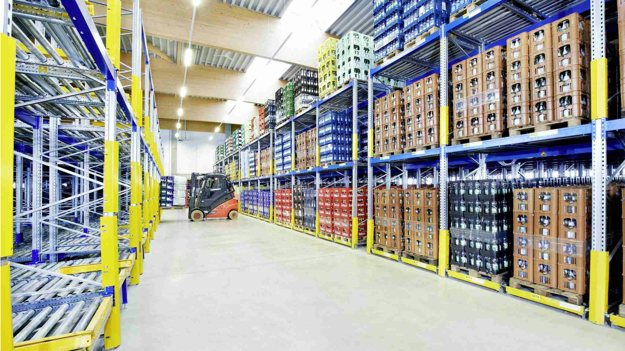 Getränke werden in einem BITO Regal gelagert. Ein Stapler lädt eine Palette mit Getränken in das Regal ein.