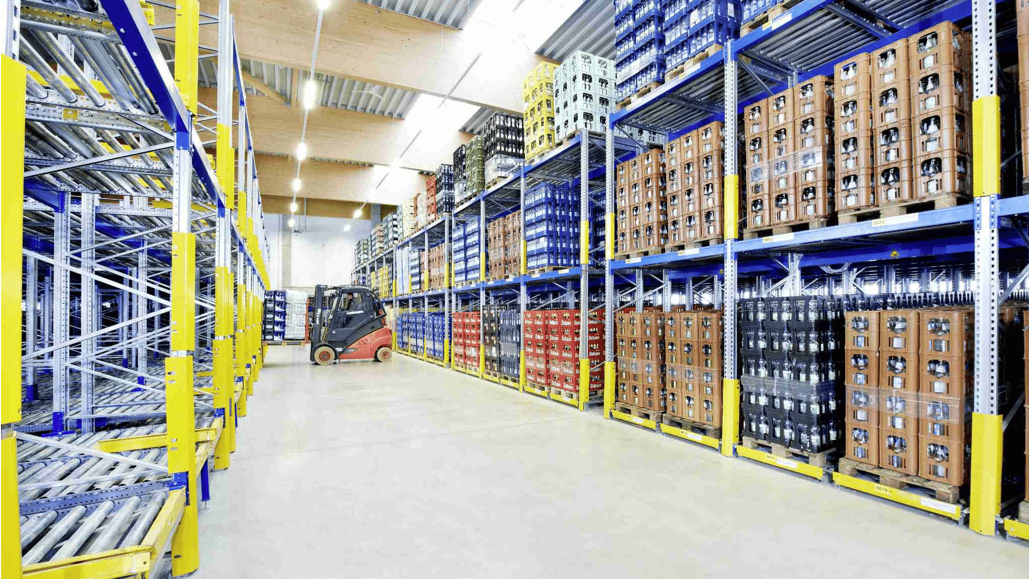 Getränke werden in einem BITO Regal gelagert. Ein Stapler lädt eine Palette mit Getränken in das Regal ein.