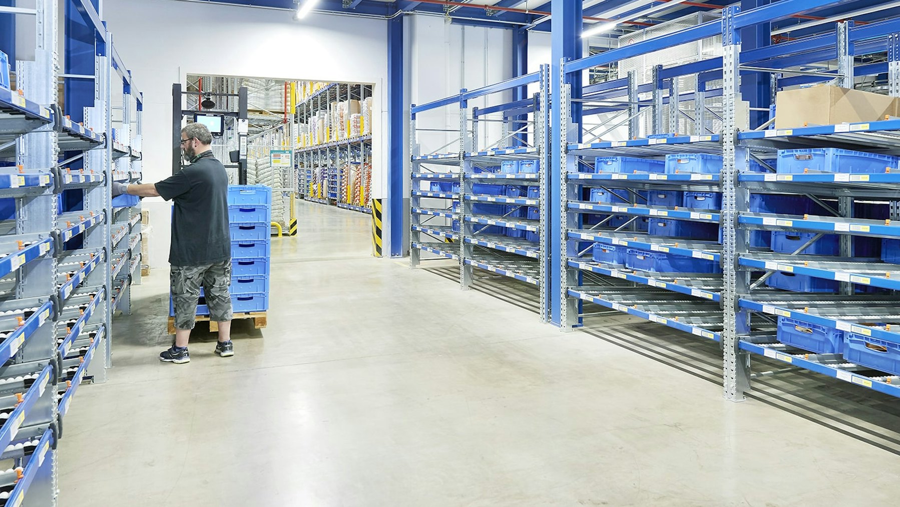 Rayonnages dynamiques colis BITO Ein Mann stellt BITO Behälter in ein BITO Durchlaufregal.