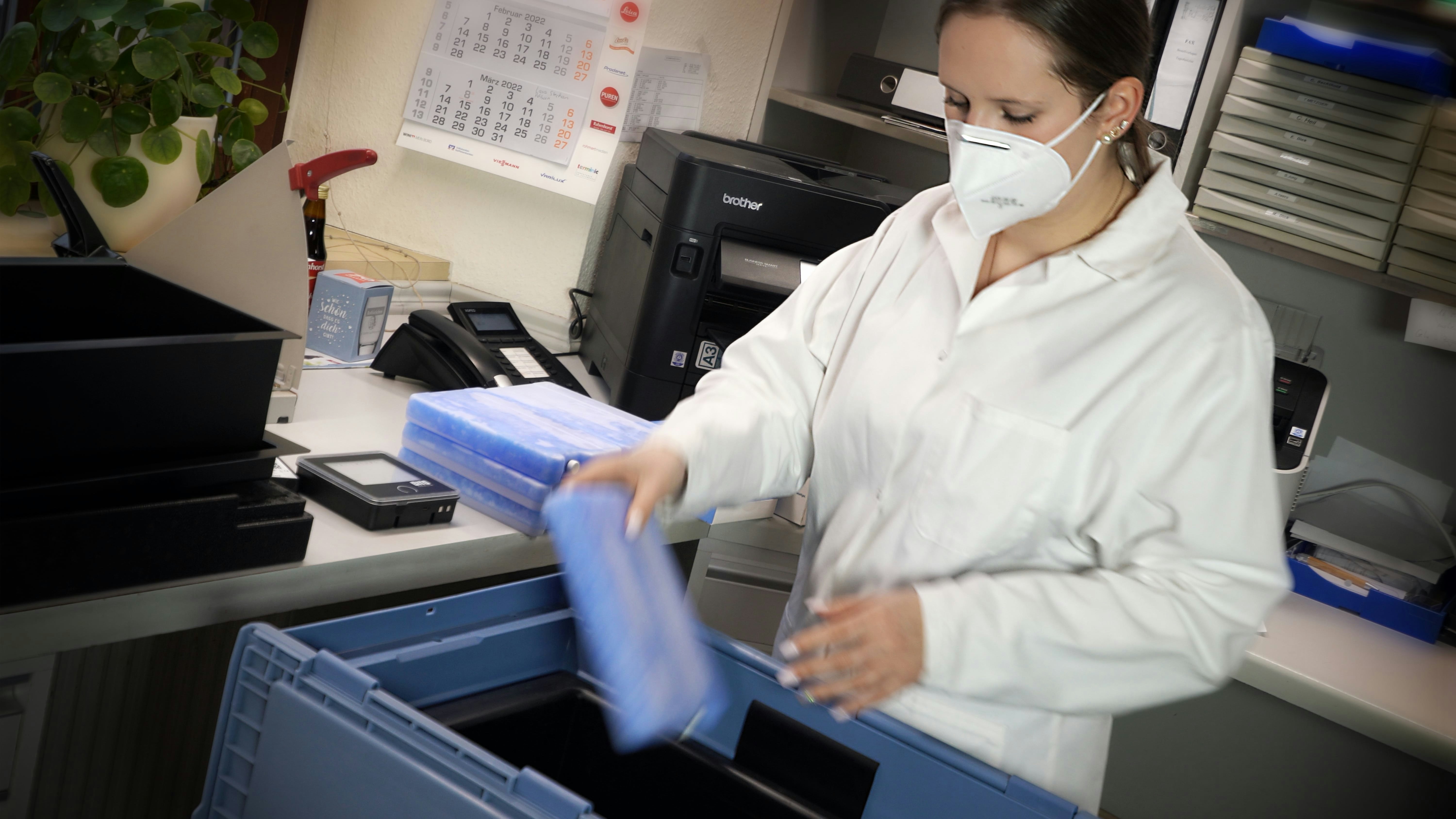 BITO Pharmabox Eine Frau im Medizinkittel und mit Maske packt Kühlakkus in einen BITO Behälter.