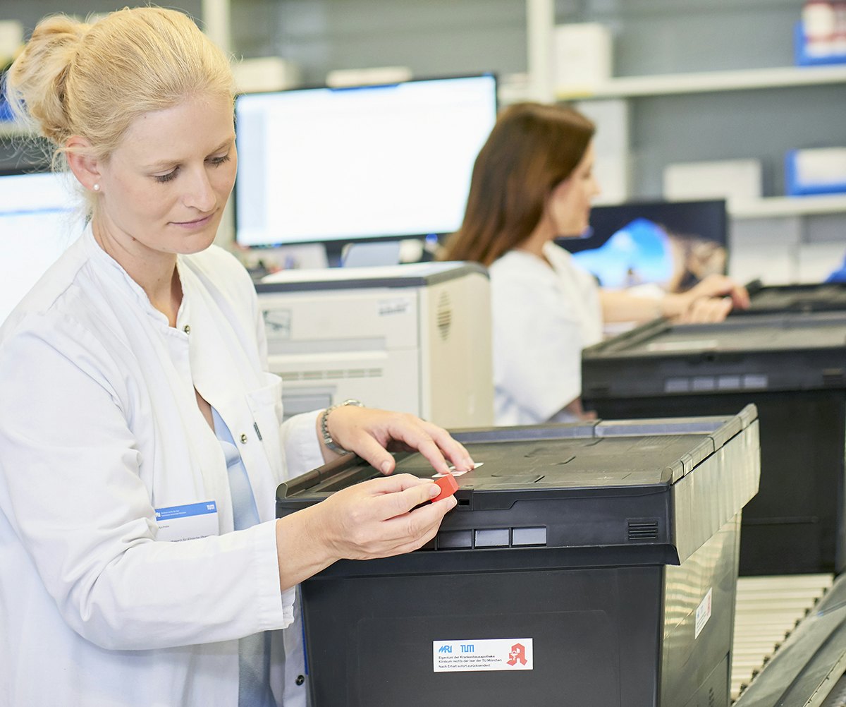 BITO Pharmabox Eine Frau im Medizinkittel schließt einen BITO Behälter, der auf Rollleisten steht.