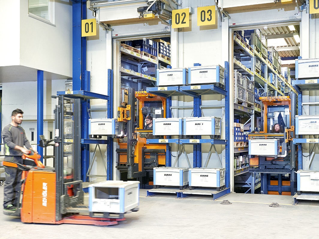 BITO SL 86 Behälter Stapler laden BITO Behälter mit der Aufschrift Claas in ein BITO Regal an der Wand. Im Vordergrund transportiert ebenfalls ein Stapler einem BITO Behälter.