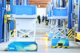 LEO Locative transportieren BITO Behälter in einer Lagerhalle.