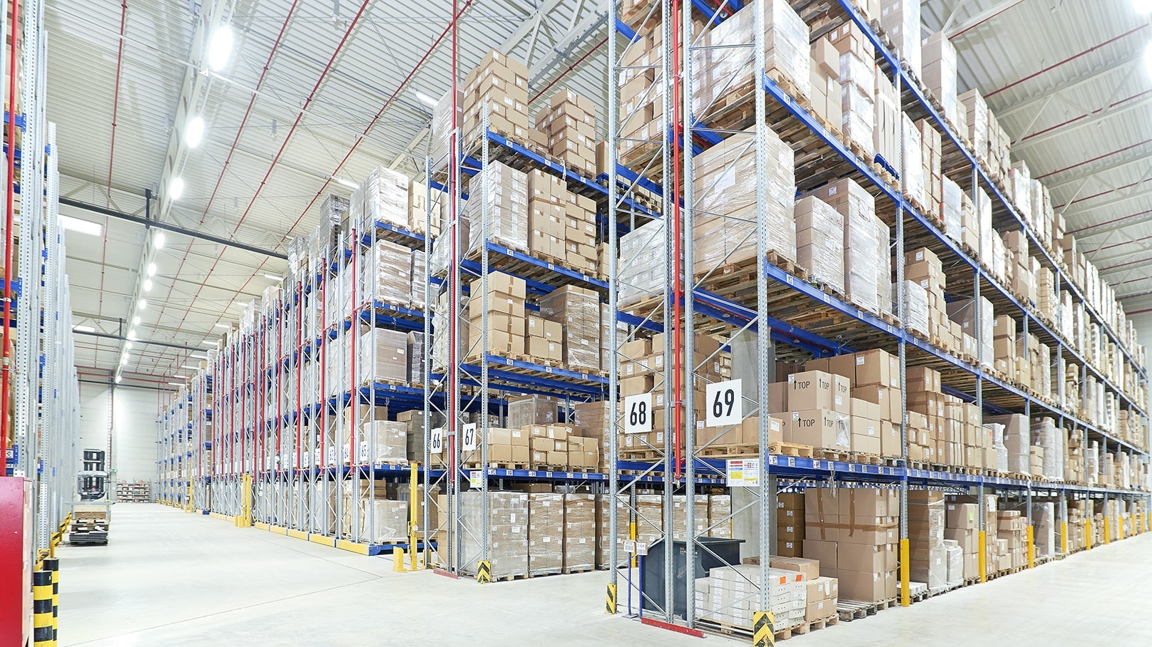 BITO Verfahrbares Palettenregal Eine große Lagerhalle in der BITO Lagerregale und Verschieberegale stehen. Diese sind gefüllt mit auf Paletten sitzenden Kartons.