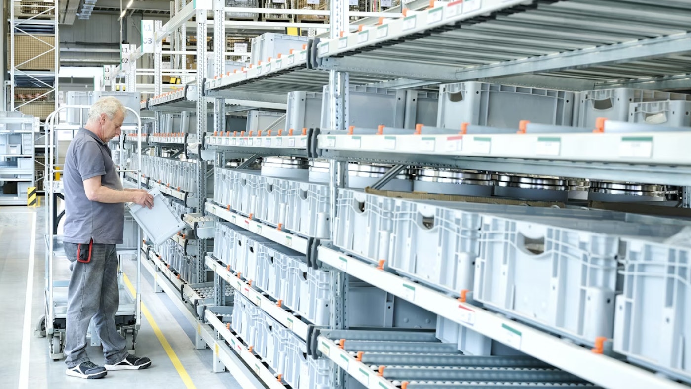 De foto laat een orderpicker aan het werk zien die een doorrolstelling met kleine bakjes vol componenten aan het aanvullen is.