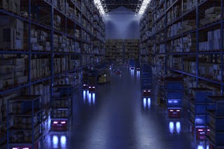 De foto toont een magazijn waar de lichten uit zijn en waar ARM's rondrijden en je ziet enkel hun koplampen.