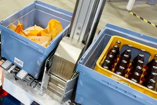 De foto toont een kunststof transportbox die wordt vervoerd door een AMR