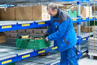 Magazijnmedewerker orderpickt magazijnbakken uit magazijnrek