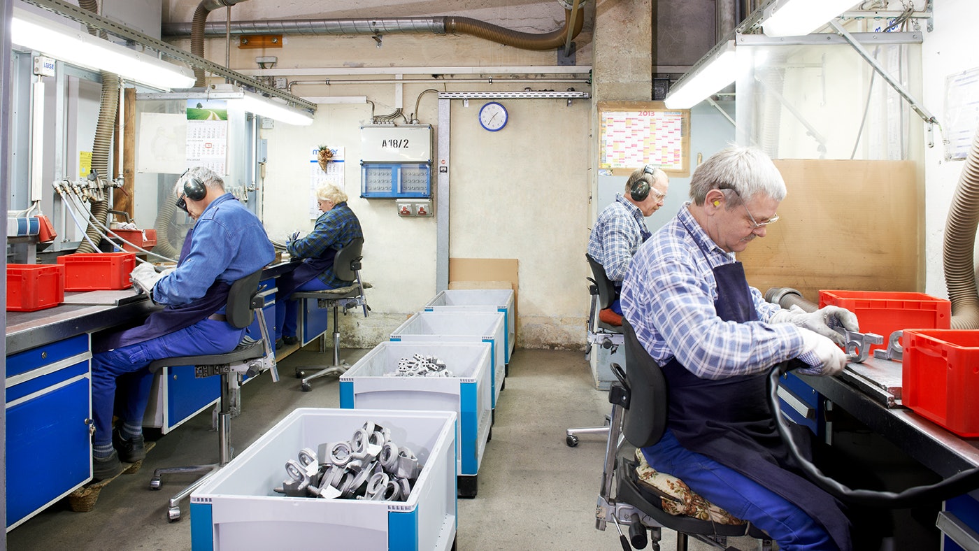 Je ziet een werkplaats waar productiemedewerkers onderdelen maken.