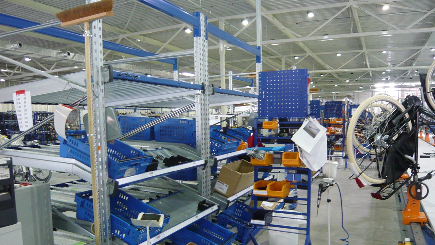 De foto toont een doorrolstelling met bakken en kleine onderdelen en een fiets