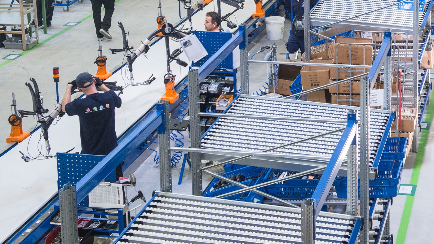 De foto toont een doorrolstelling en montage medewerker die een fiets in elkaar steekt.