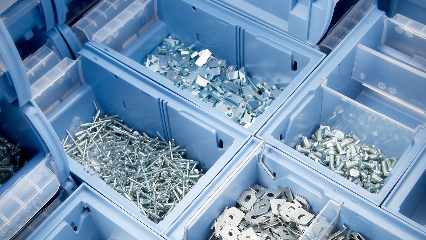 De foto toont magazijnbakken met vijzen en de bak is onderverdeel met transparante tussenschotten om de verschillende vijzen en moeren te scheiden.