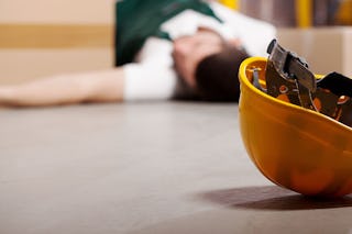 Ein Helm, im Hintergrund liegt ein Mann