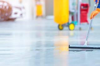 Mitarbeiter reinigt den Boden eines Industrielagers