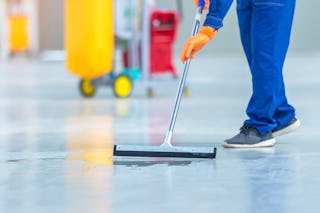 Mitarbeiter reinigt den Boden eines Industrielagers