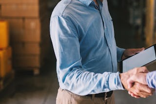 Zwei Männer beim Handshake, einer hat ein Tablett in der Hand