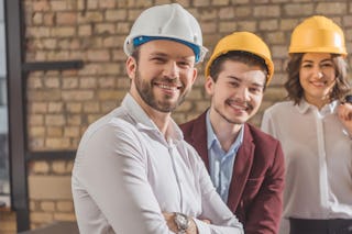 Zwei Männer und eine Frau mit Bauhelmen