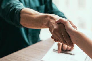 Zwei Personen beim Handshake, nach der Unterzeichnung eines Dokuments