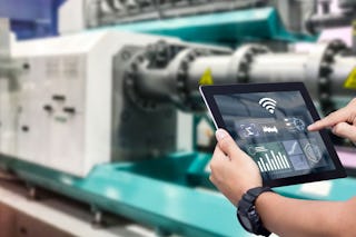 Eine Person überprüft die Produktion über ein Tablett