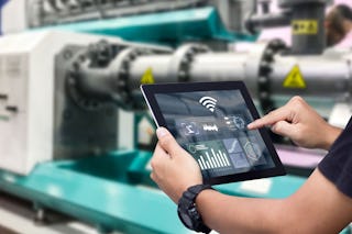 Eine Person überprüft die Produktion über ein Tablett