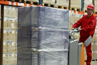 Zwei Arbeiter in einem Lager. Einer bewegt eine optimal verpackte Palette.