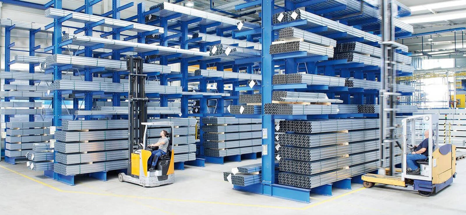 Arbeiter in Flurförderzeugen an Kragarmregalen